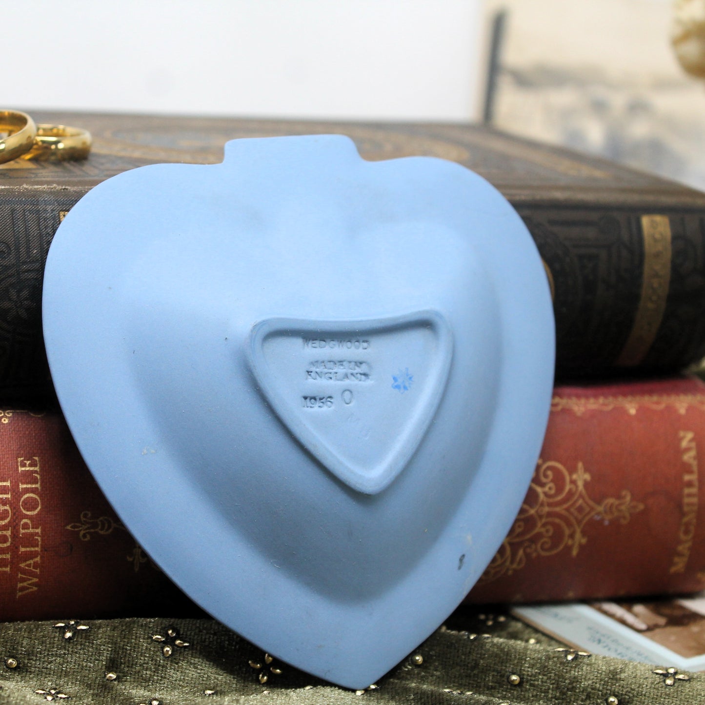 Blue heart-shaped Wedgwood dish shown upside down on top of books with a blurred background
