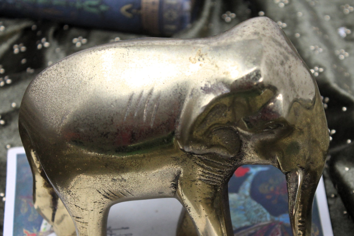 Vintage Indian copper and brass elephant sculpture standing on top of scattered vintage papers and photographs.
