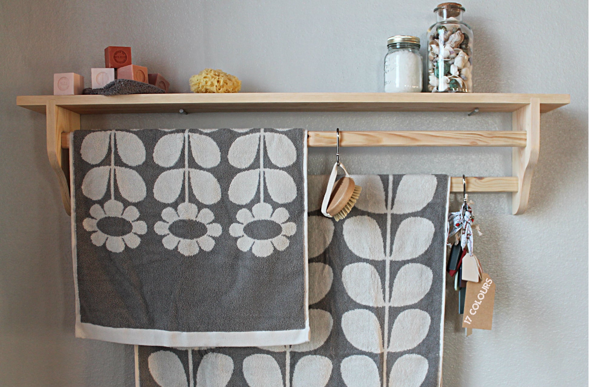 Natural wood towel rack with shelf, featuring Danish oil finish and styled with soft grey textiles and vintage-inspired accessories."