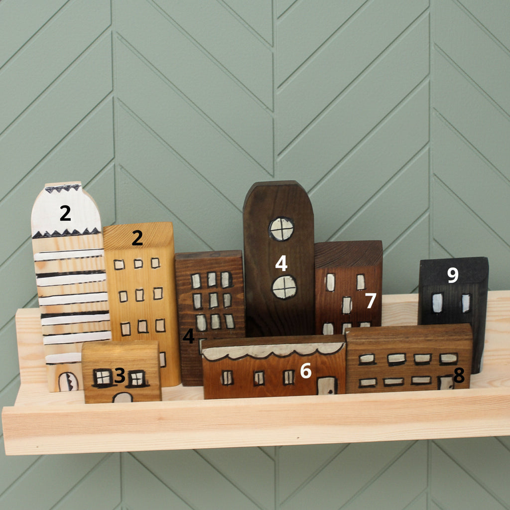 A light natural wood floating shelf mounted on a textured turquoise wall, styled with a wooden cutting board, a bottle of olive oil, three glass spice jars, and a small potted succulent.