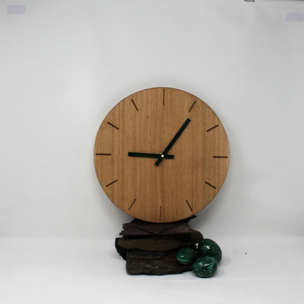 large round wooden clock made of oak with dark green metal hands