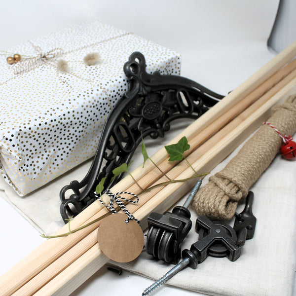 Flat lay of a Victorian ceiling airer kit featuring smooth wooden laths, black cast iron brackets, rope, and pulleys — ideal for traditional drying solutions.