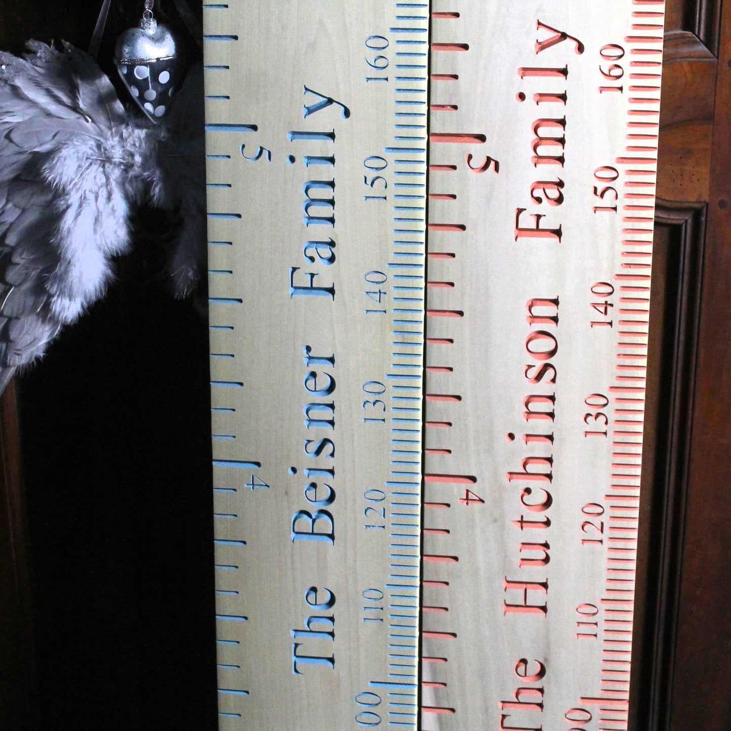 Two wooden rulers with engraved family names and measurements.