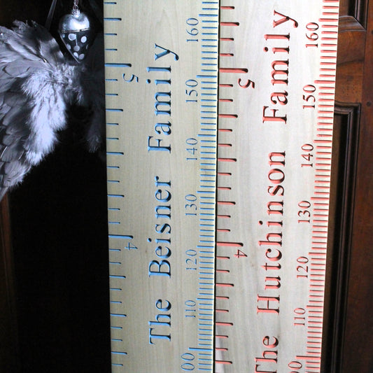 Two wooden rulers with engraved family names and measurements.