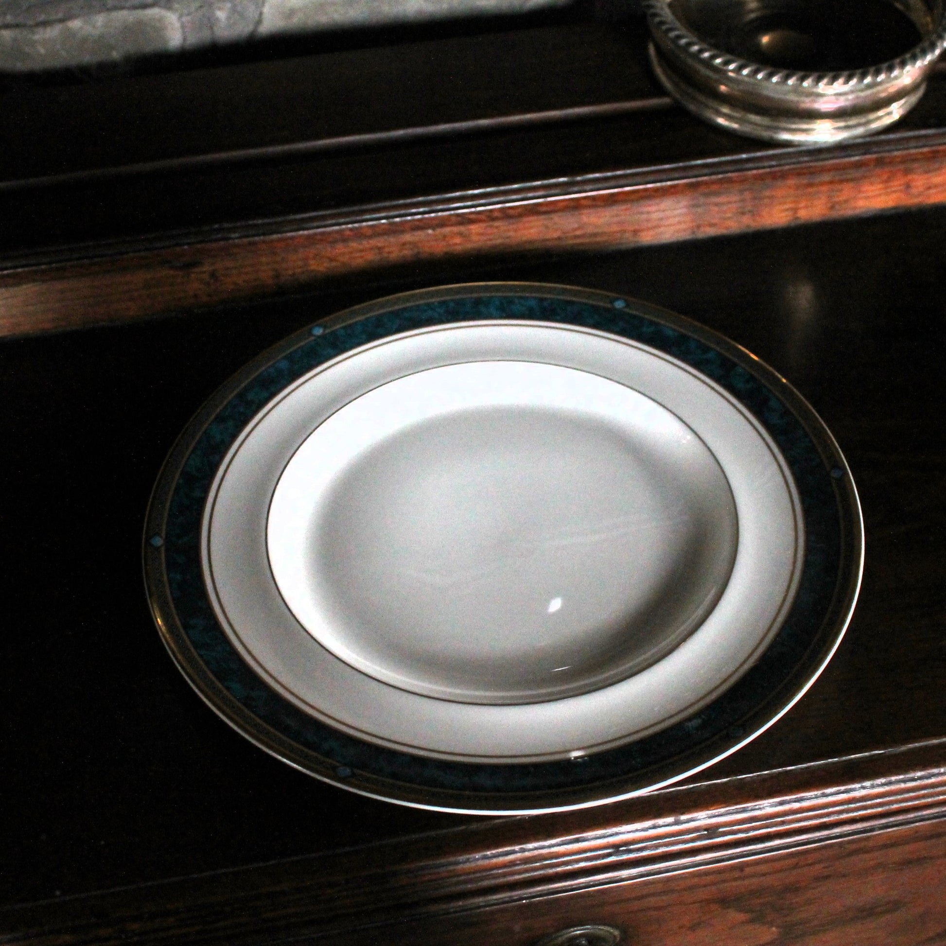 White Royal Doulton plate plate with green rim on a dark wooden surface