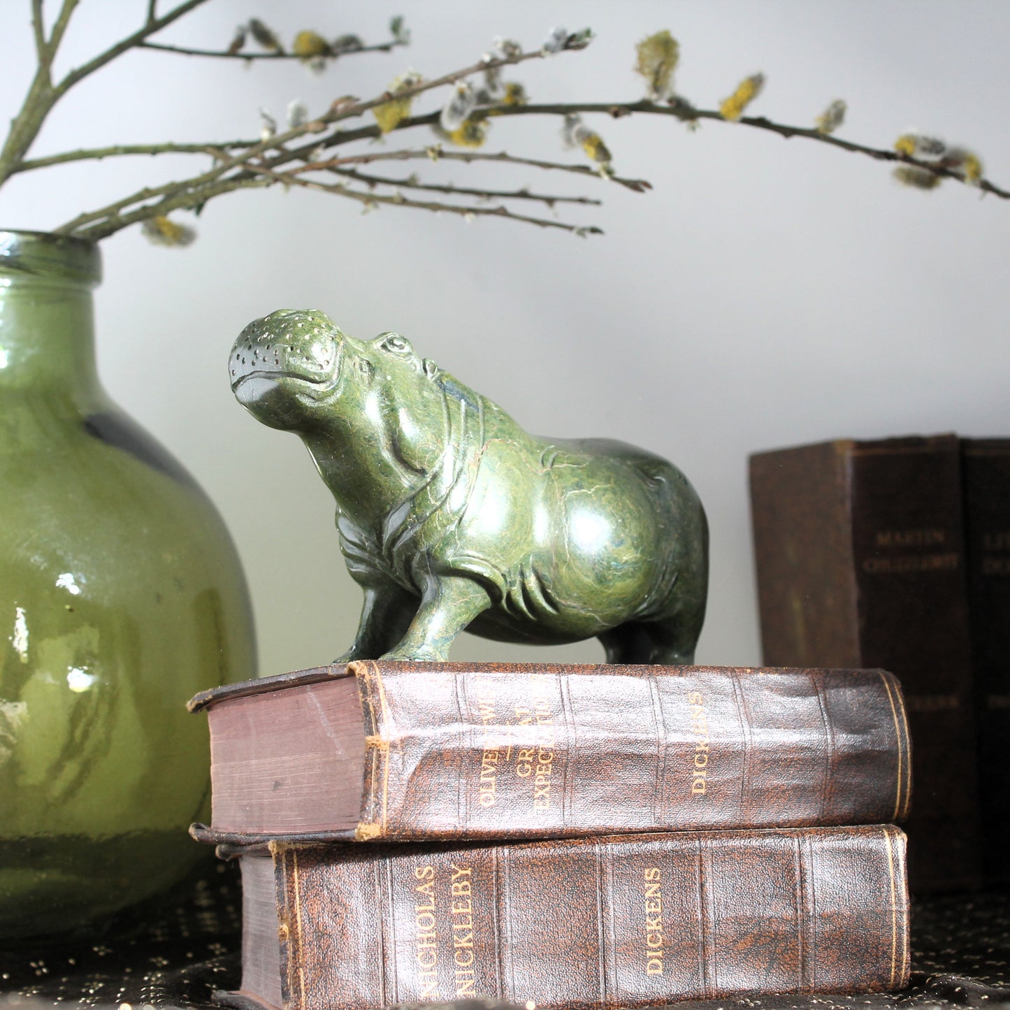 African Shona carving hippo made of verdite shown on op of antique books
