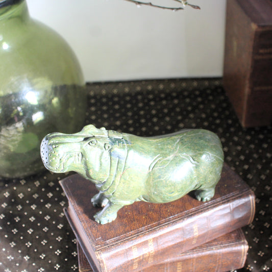 Green stone hippo carving on top of a pile of books