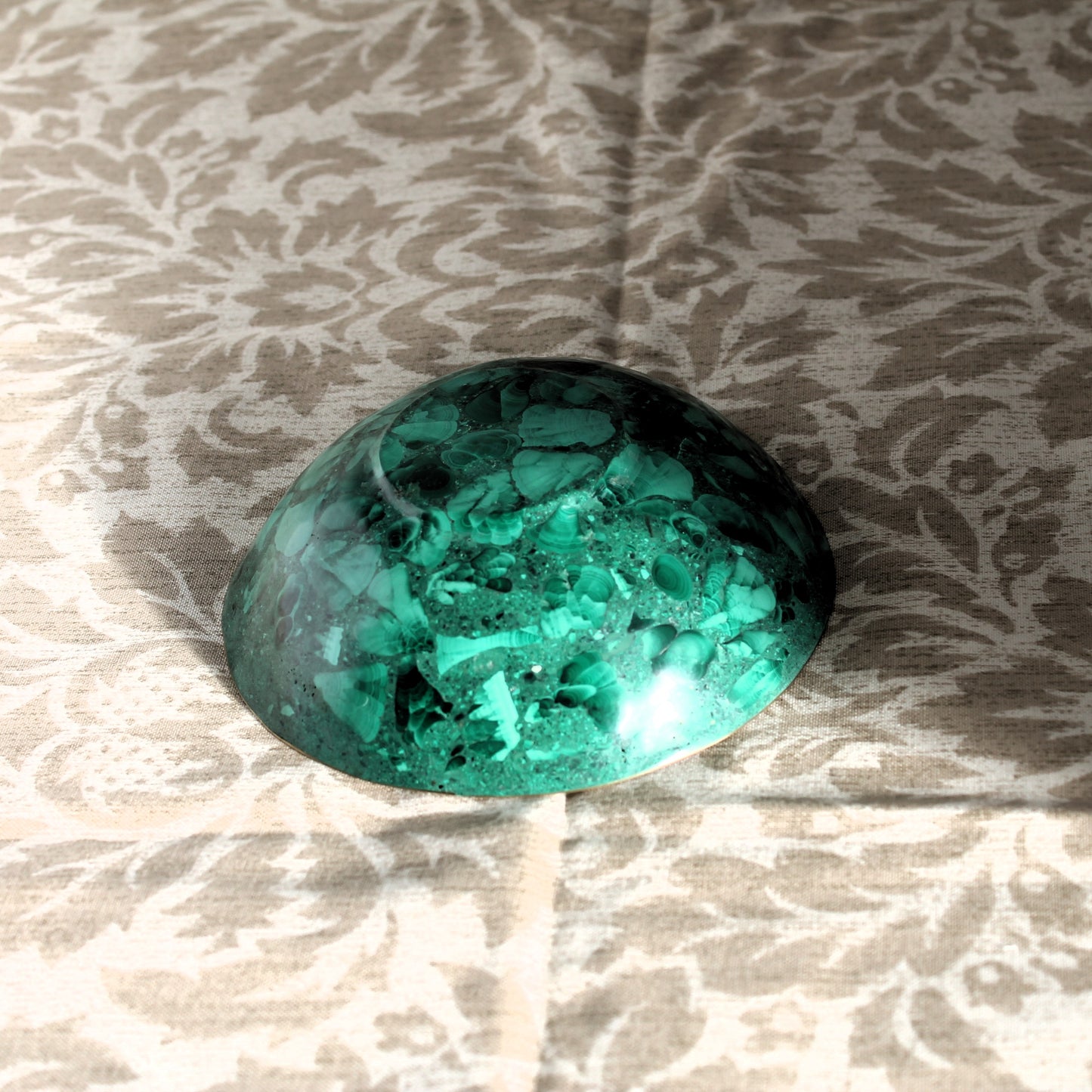 Green gemstone dish on a textured beige background
