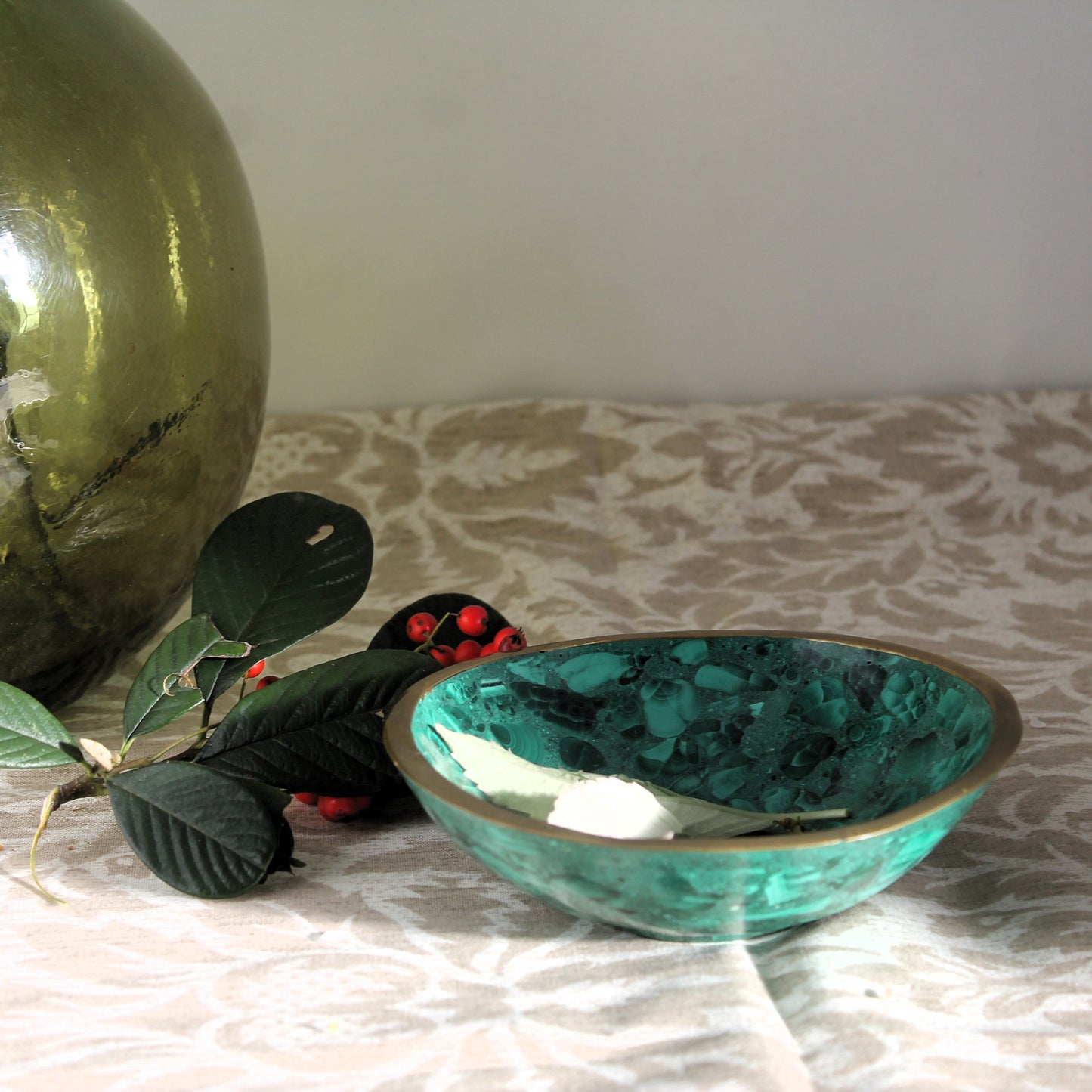 Vintage malachite cbowl on a patterned surface with decorative elements.