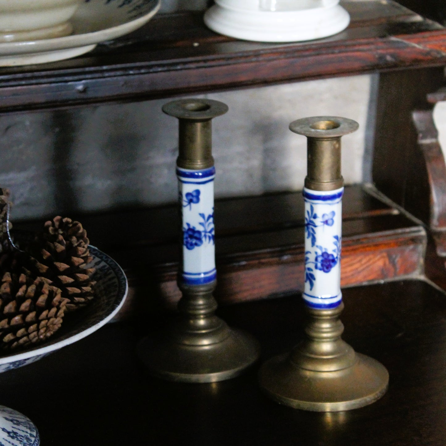 Pair of decorative brass and ceramic blue and white candlesticks on a wooden dresser