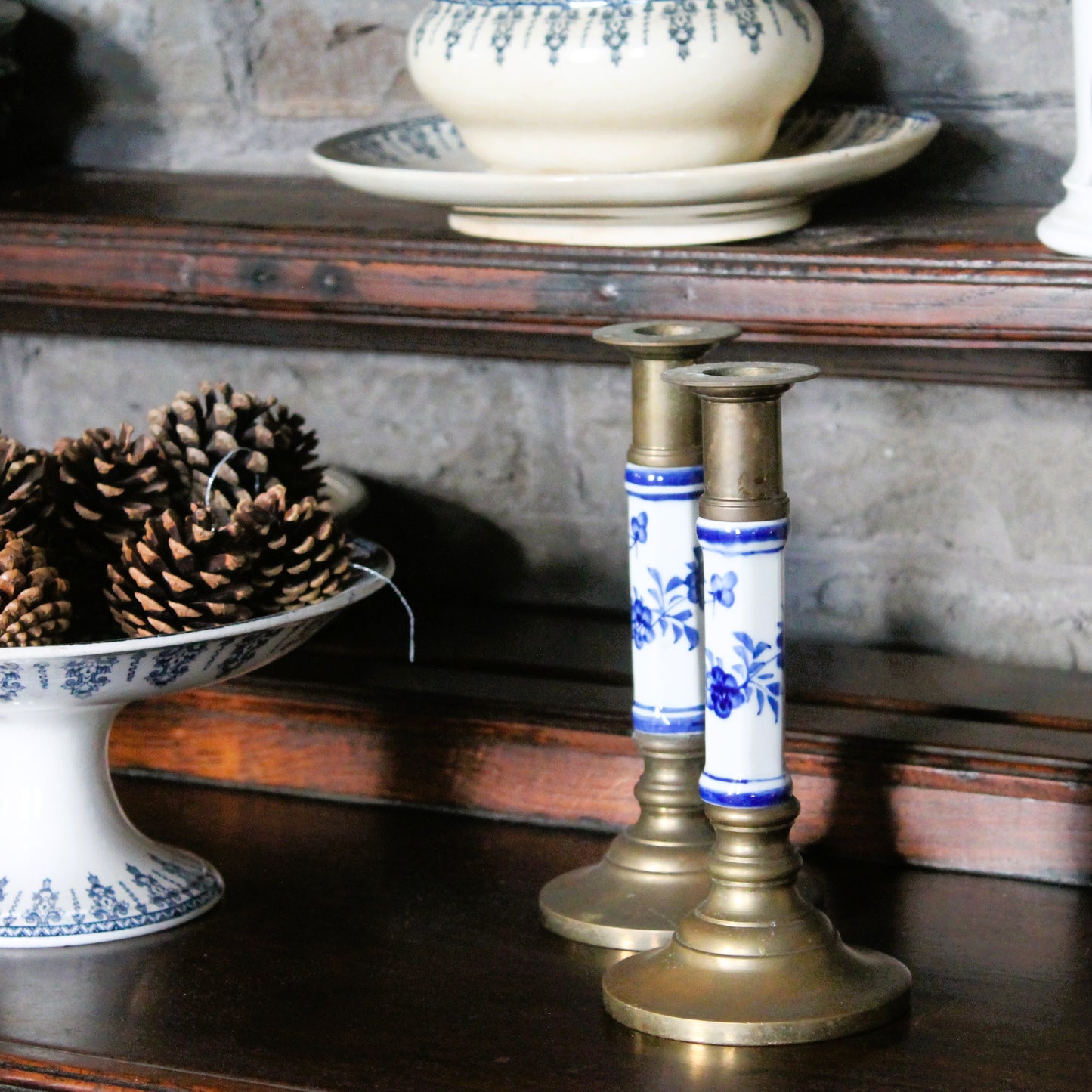 Delft-style blue and white brass candlestics on a wooden shelf