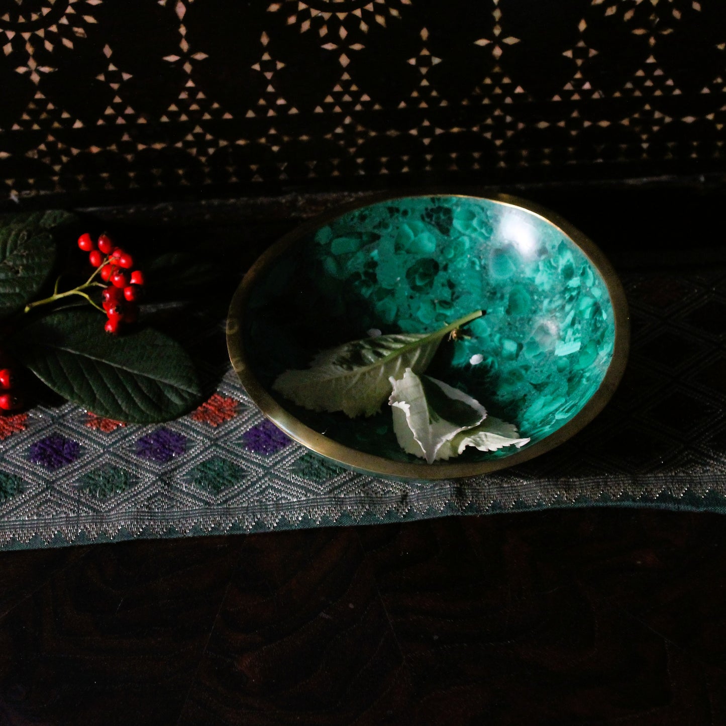 Malachite deorative dish with leaves and berries on a textured surface