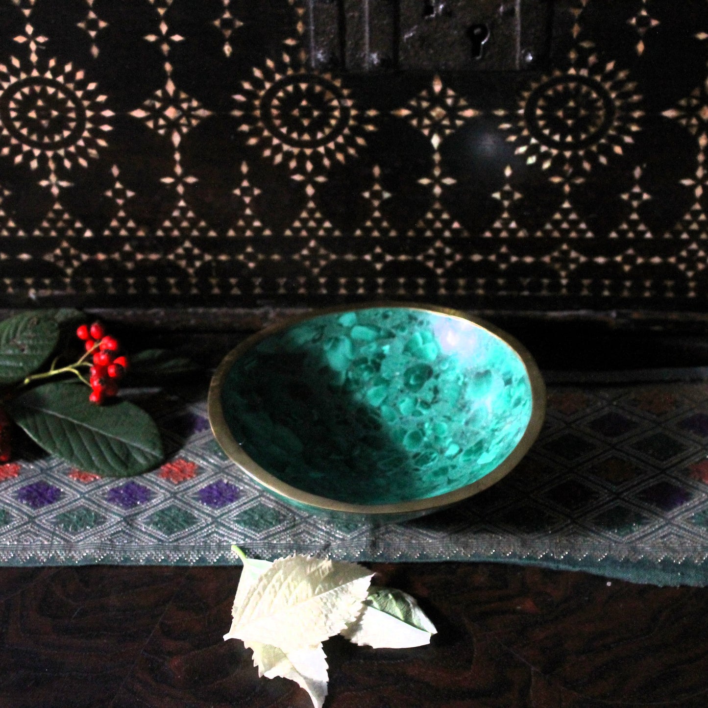 Green decorative stone bowl on a textured surface with decorative elements