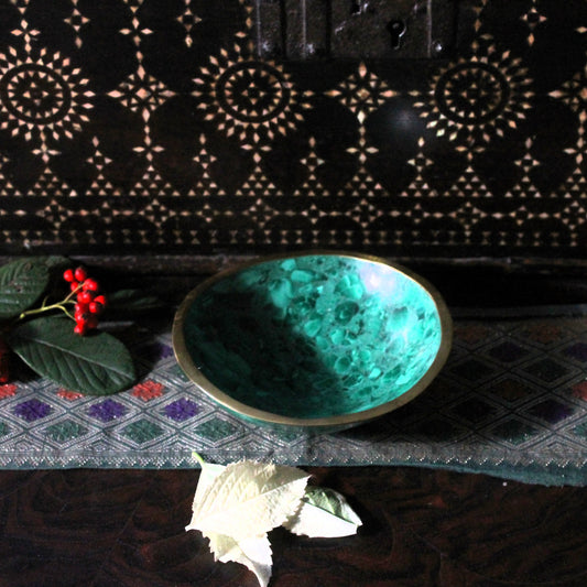 Green decorative stone bowl on a textured surface with decorative elements