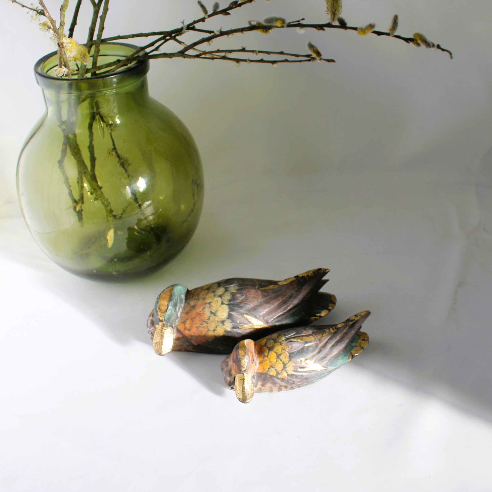 Two metallic bird figurines on a white surface