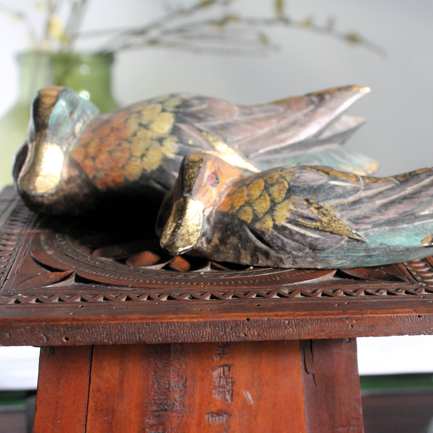 Decorative duck sculptures on a wooden stand with a blurred background