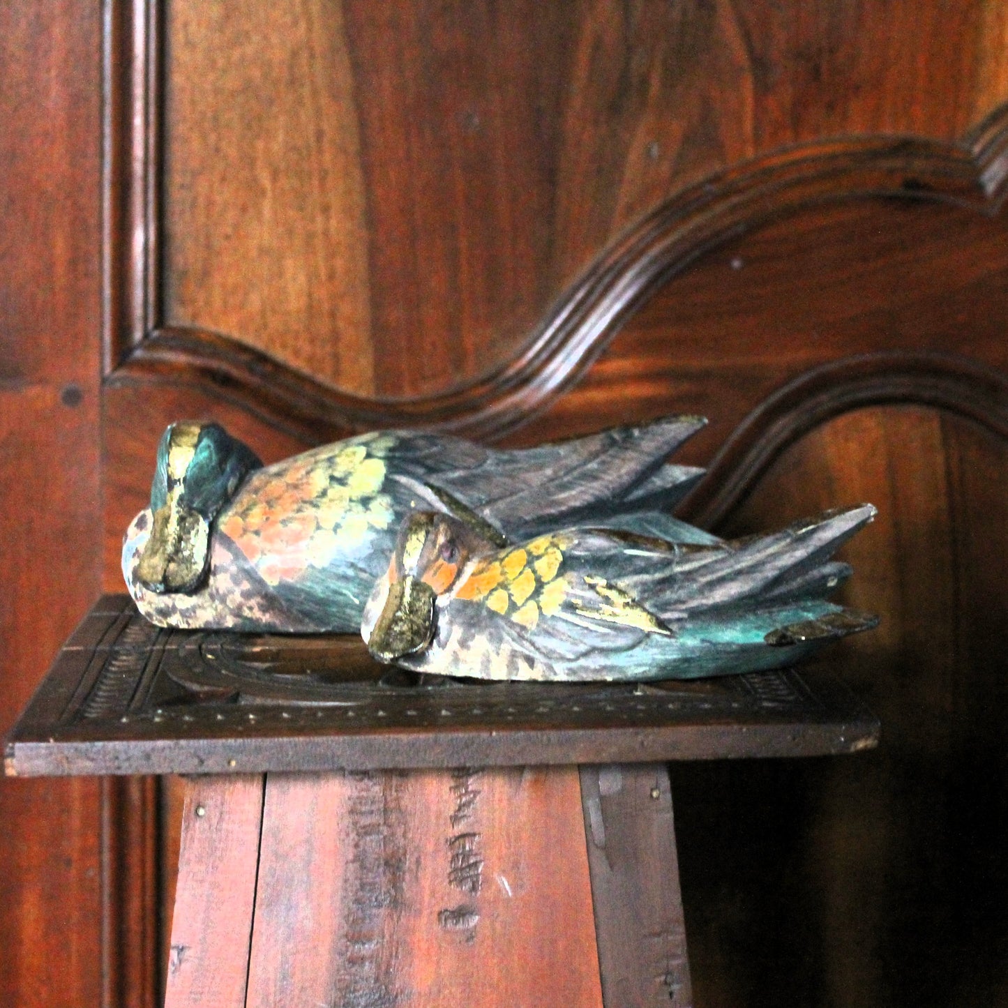 Decorative duck sculptures on a wooden surface with a wooden background