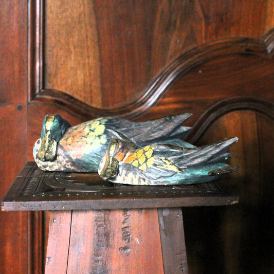 Decorative duck sculptures on a wooden surface with a wooden background