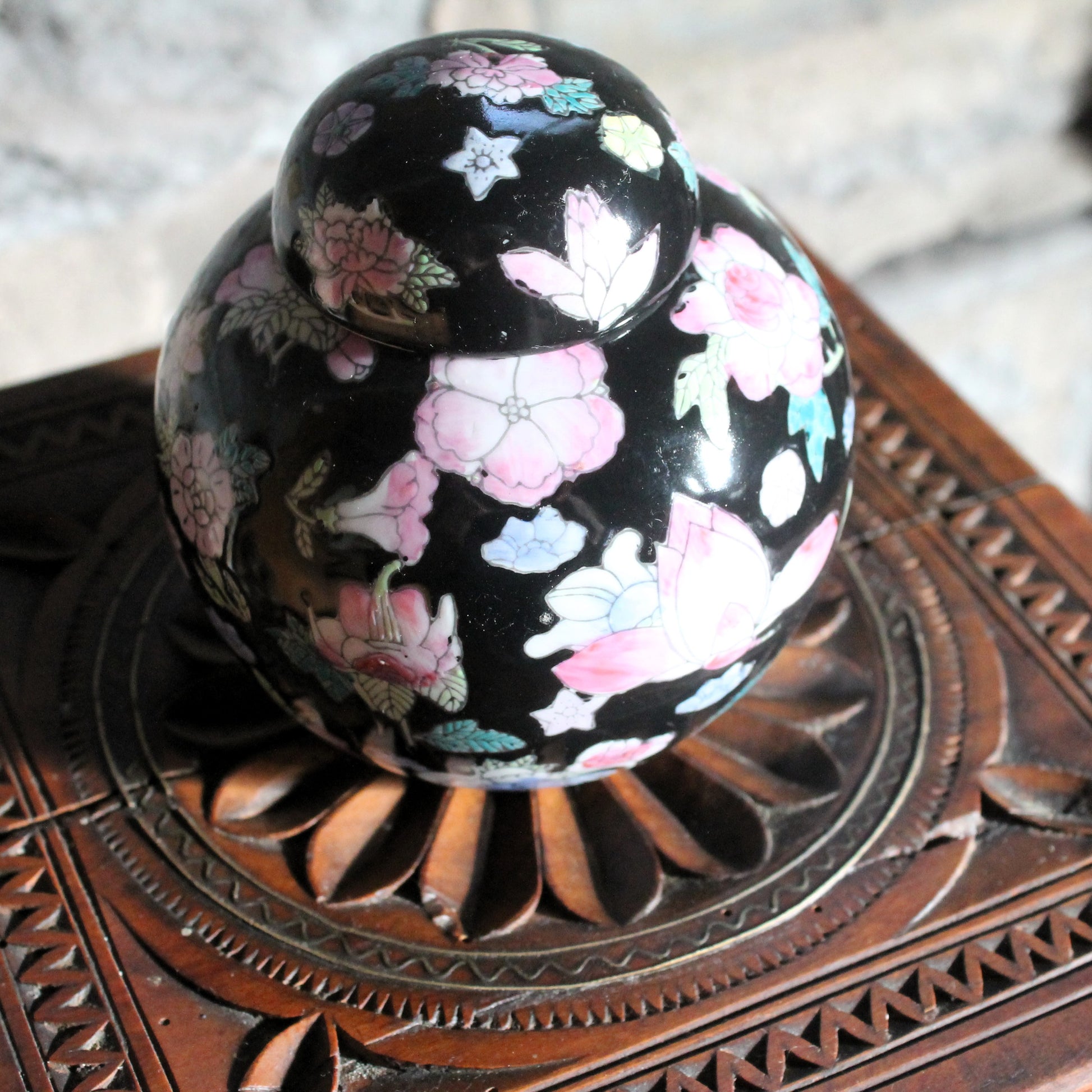 ginger jar with enamel flower decoration on a wooden table