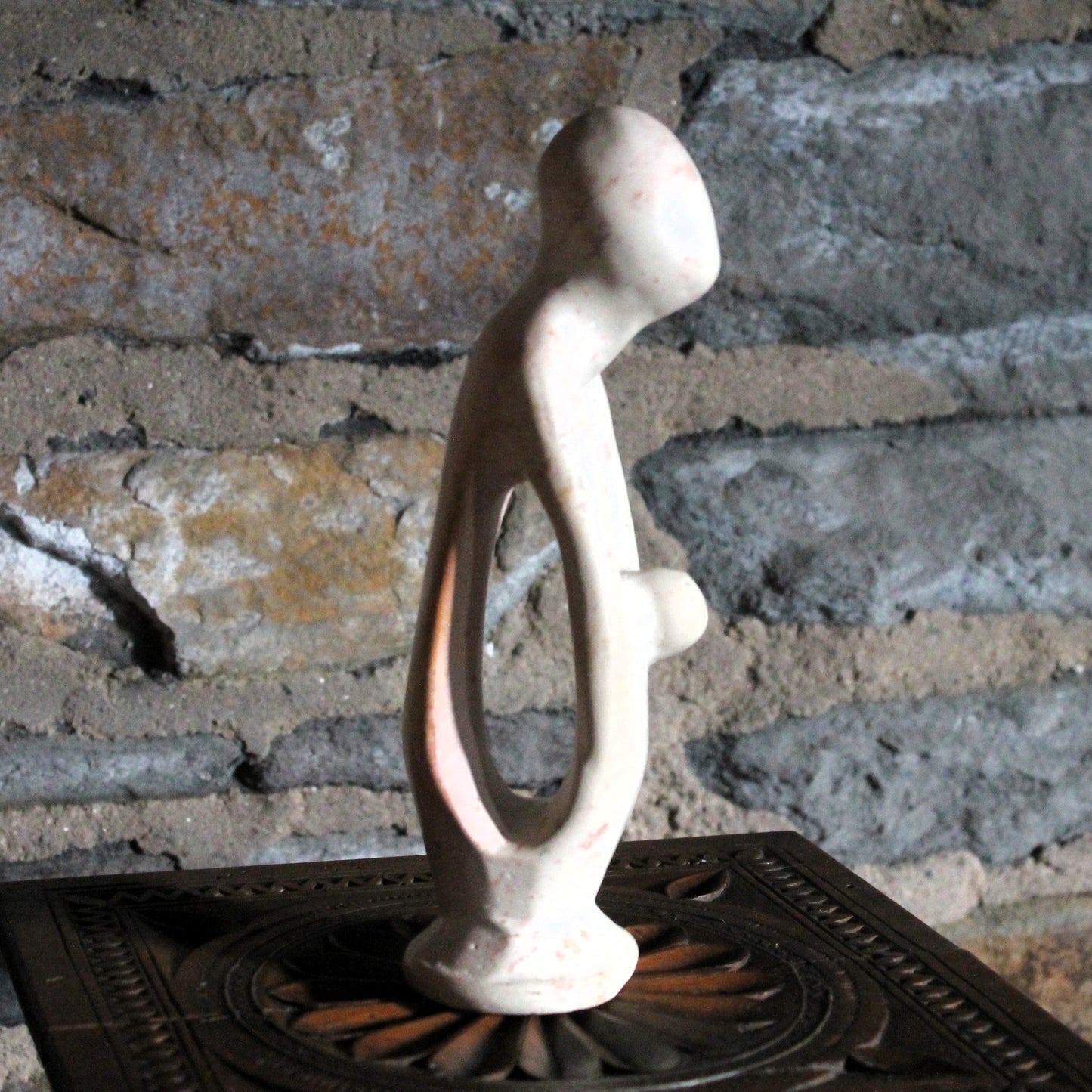 Mother and cild soap stone figurine on a stone wall background
