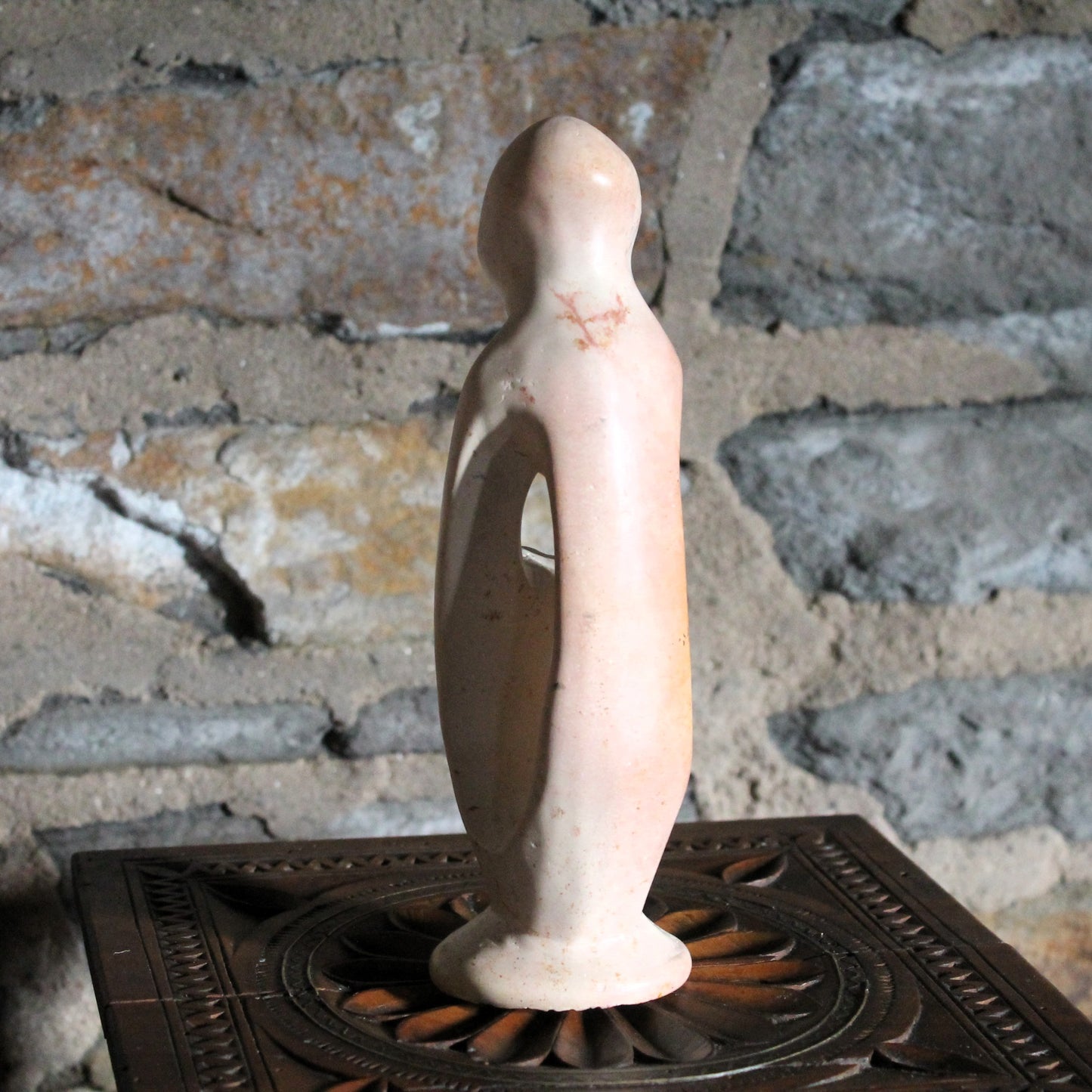 Decorative mother and child sculpture on a wood surface with a rustic background