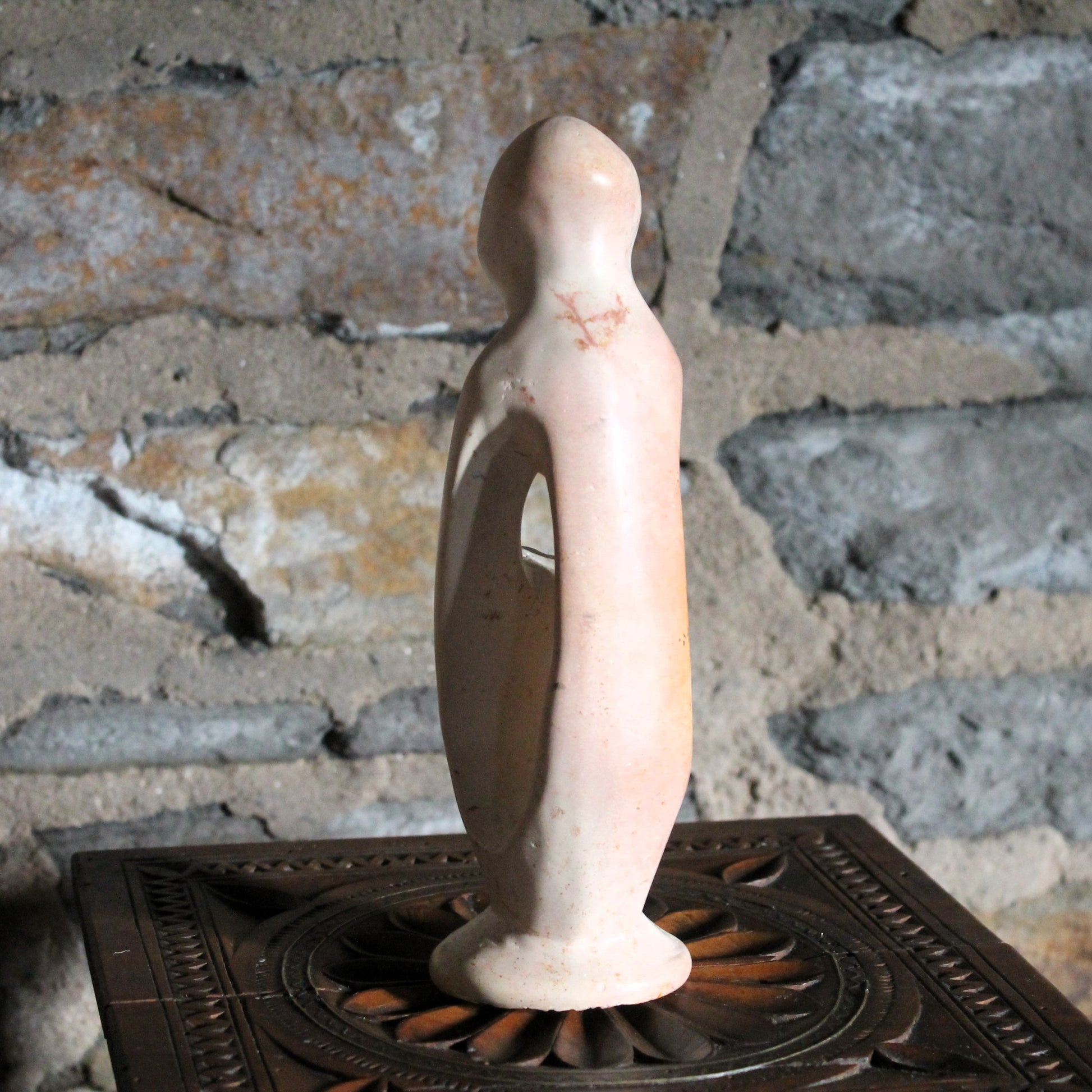 Decorative mother and child sculpture on a wood surface with a rustic background
