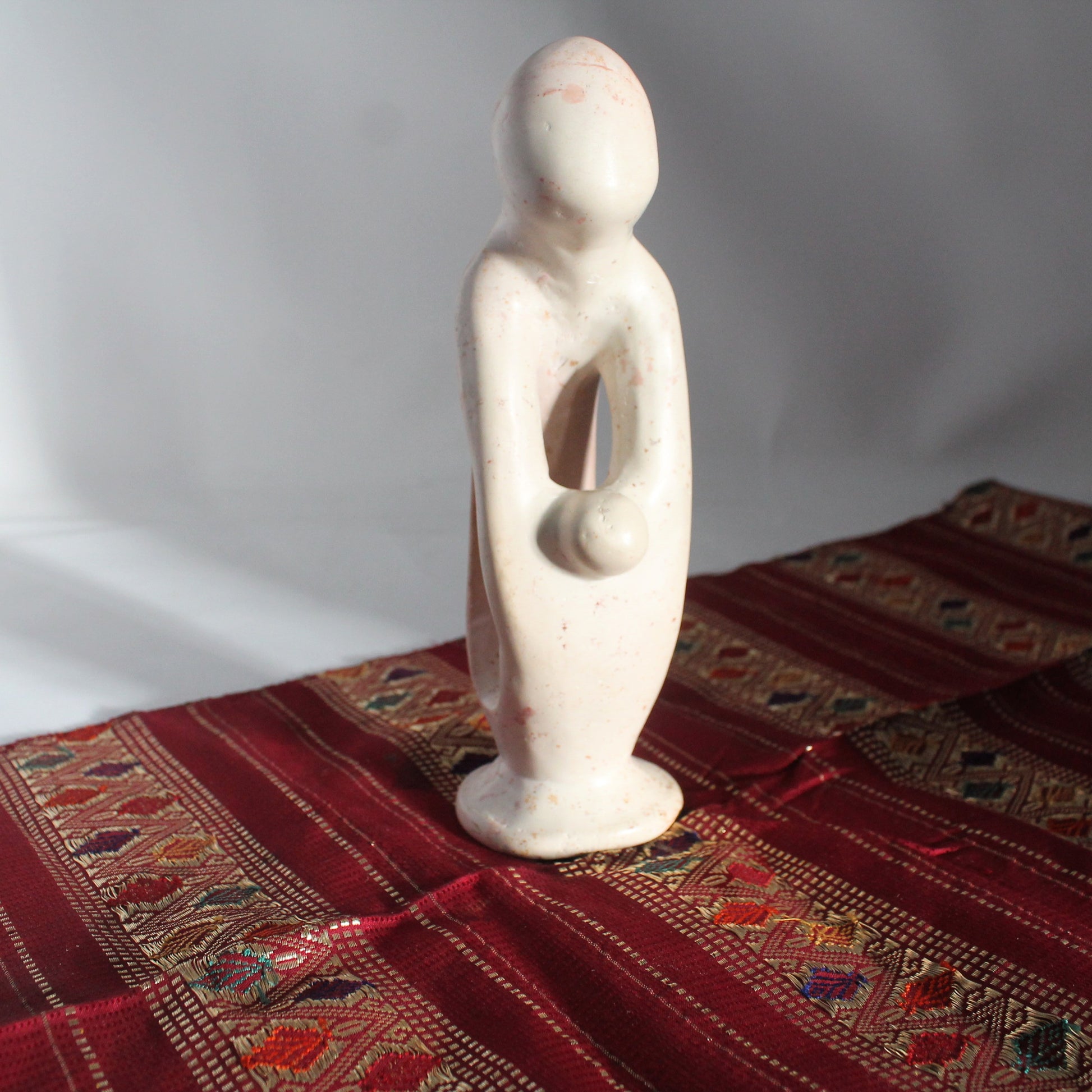 White soap ston African art figure on a red patterned fabric