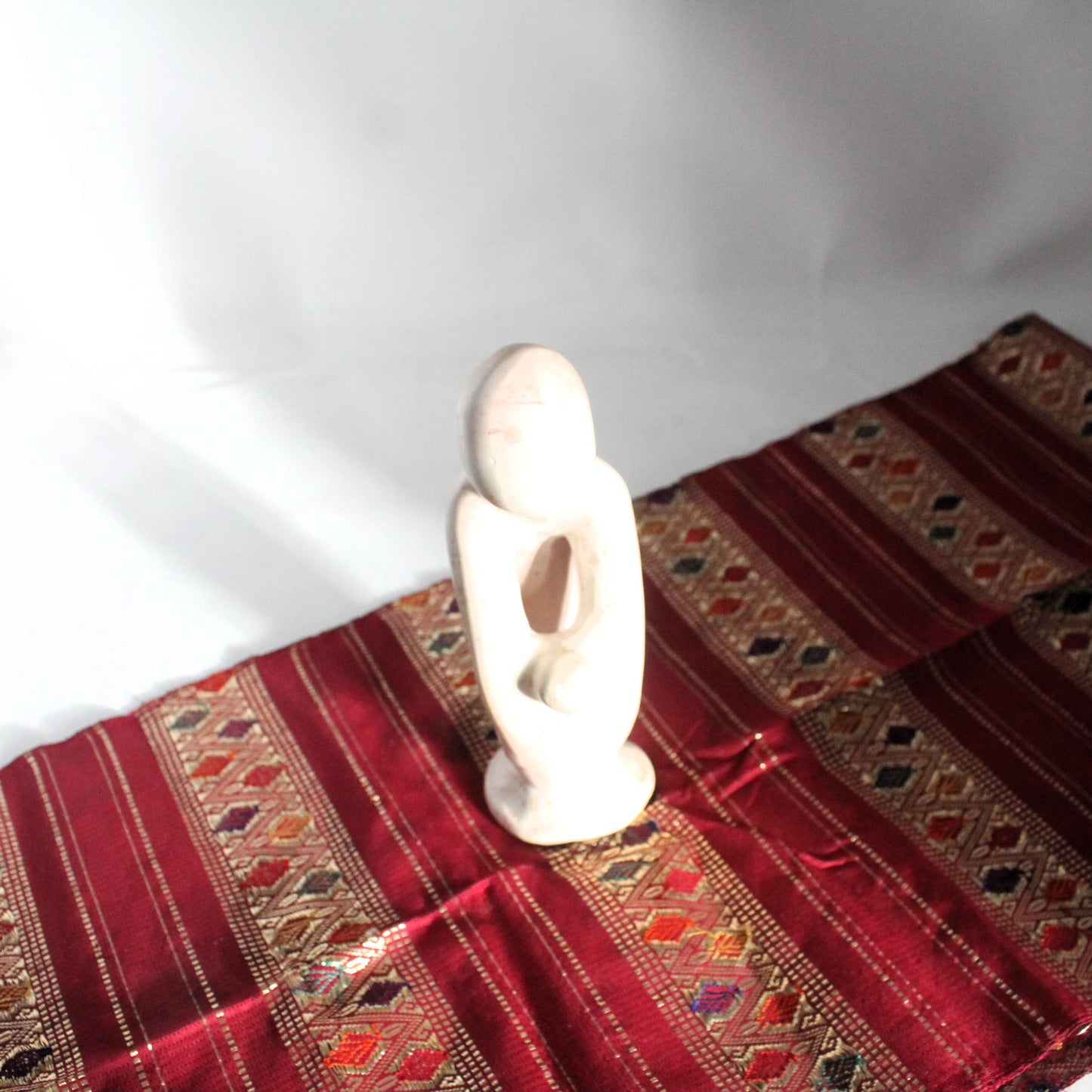 White African sopa stone carved modern sculpture on a red patterned fabric