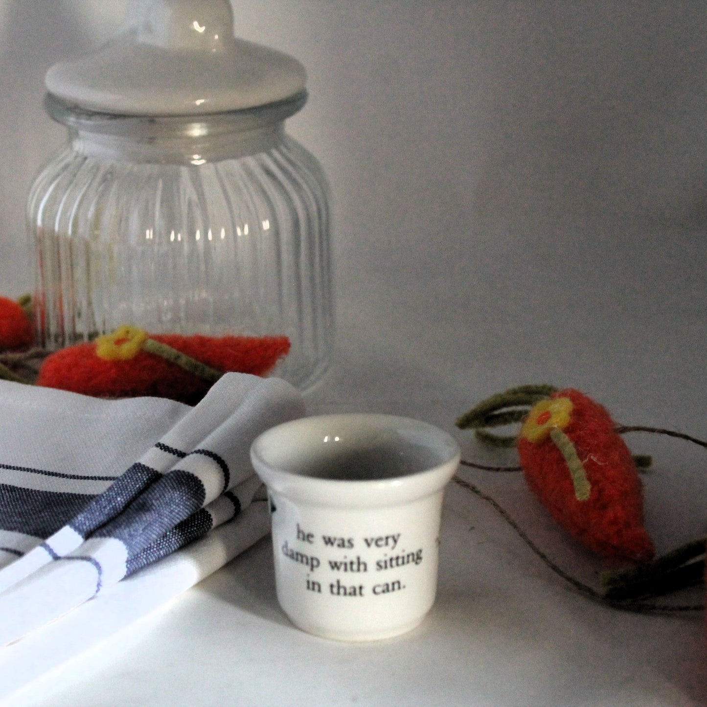 Porcelain children egg-cup on a white cloth with felt carrot ornament