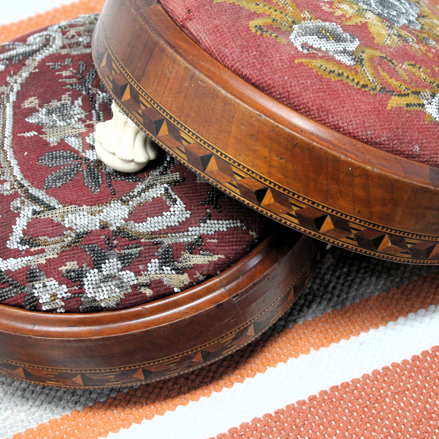 Round wooden stool with embroidered red cushion on a patterned rug