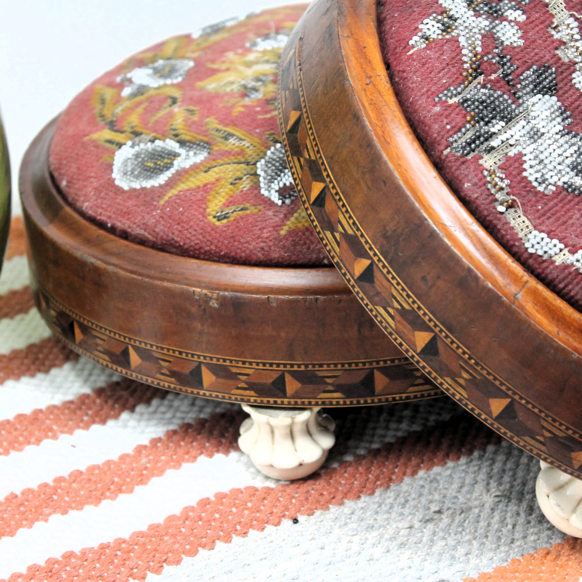 Round wooden tonbridge work stool with floral fabric top on a striped fabric background
