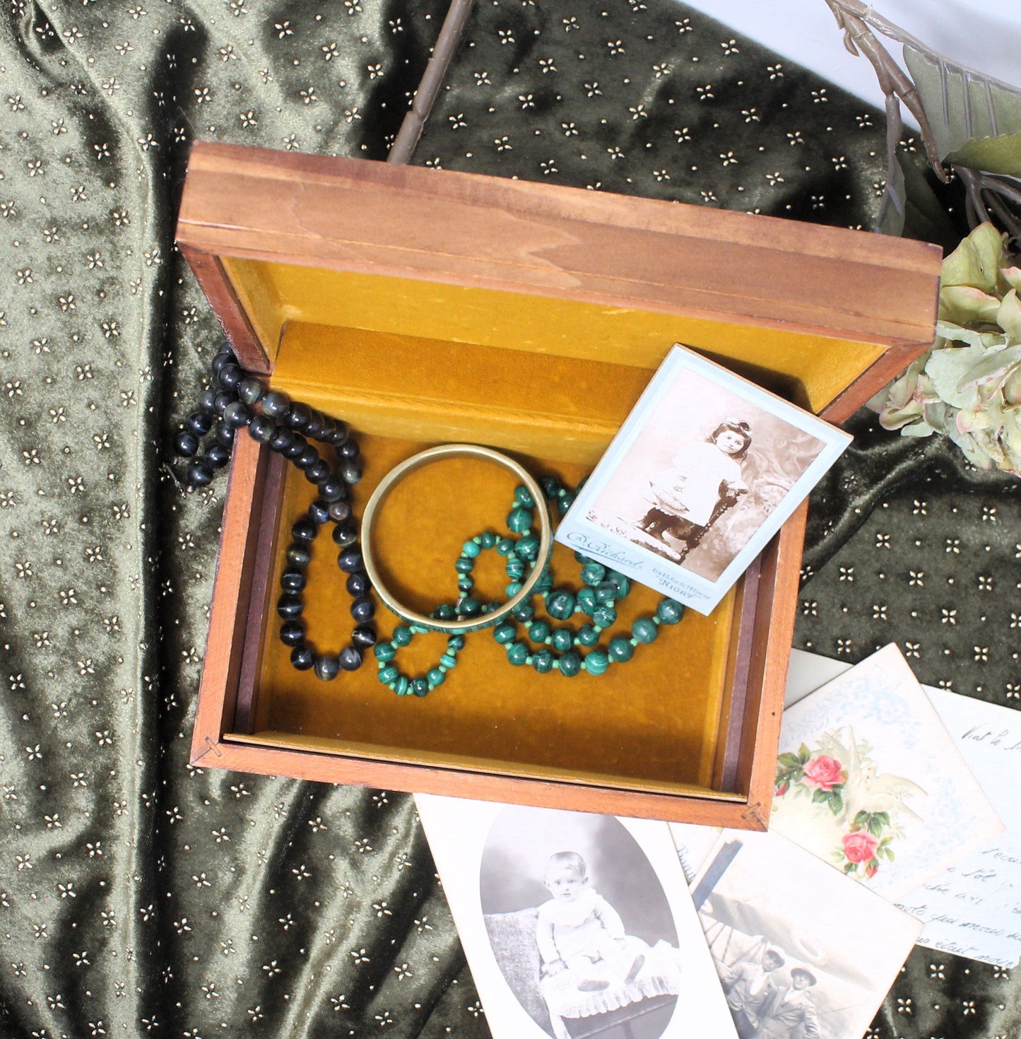 Wooden box with jewelry and vintage photos on a textured fabric background