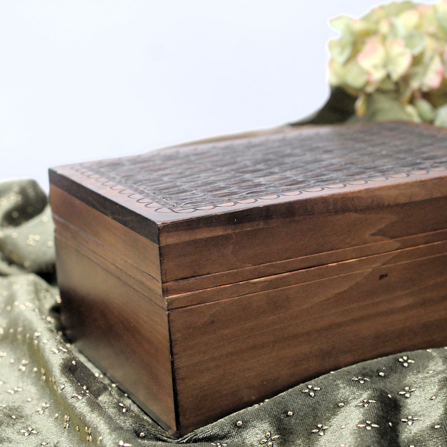 Wooden box with intricate carvings on a green fabric background