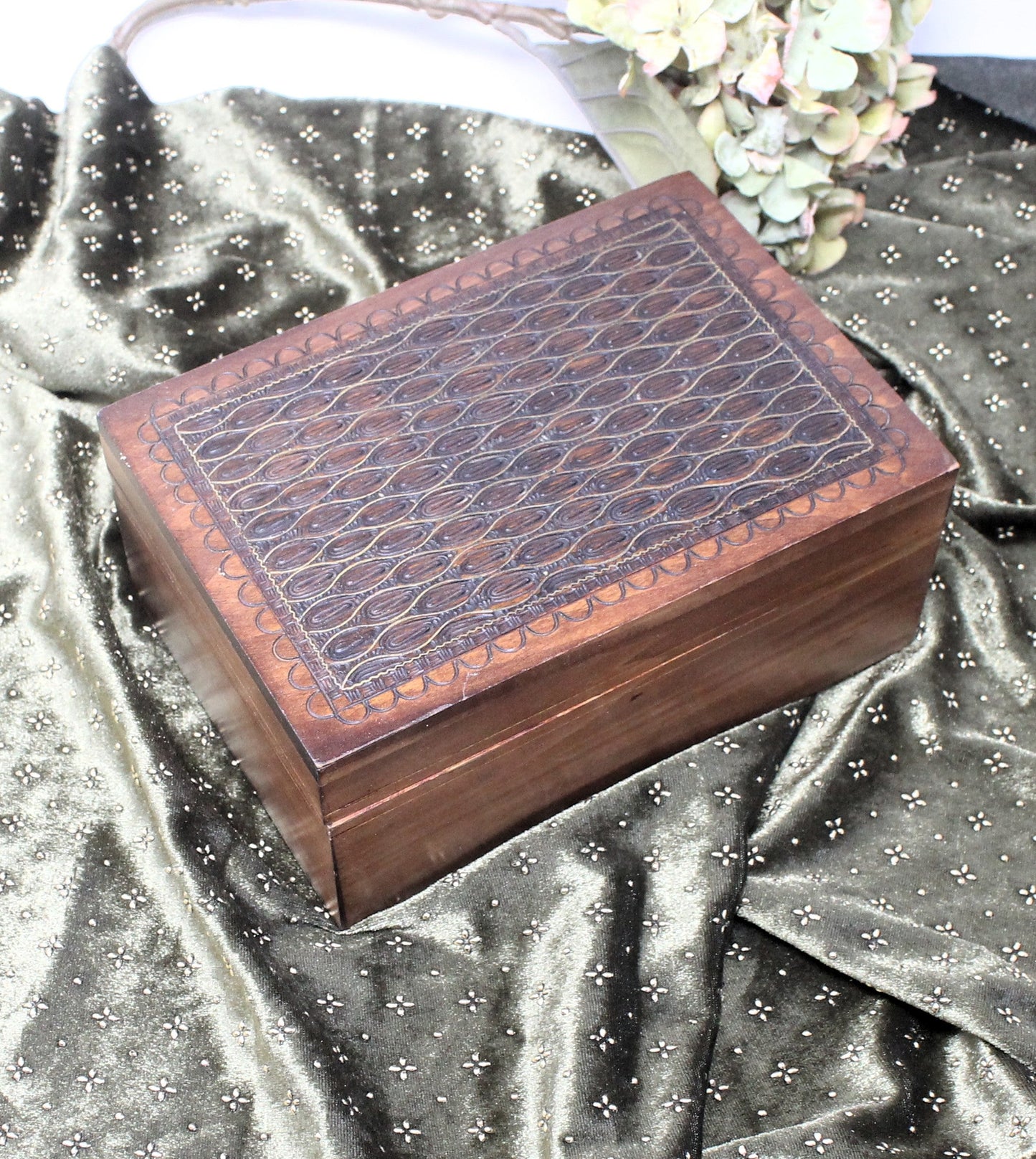 Wooden jewelry box with embossed design on a metallic silver fabric background