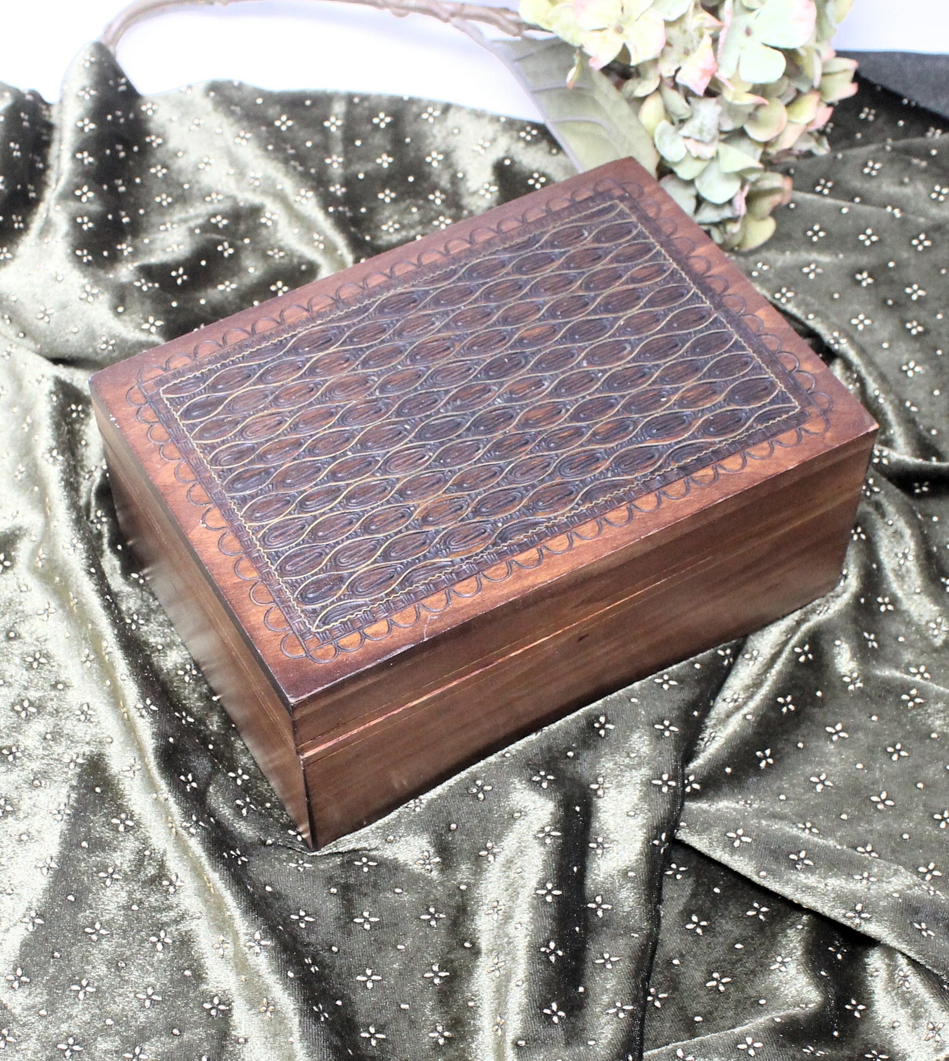 Wooden jewelry box with embossed design on a metallic silver fabric background