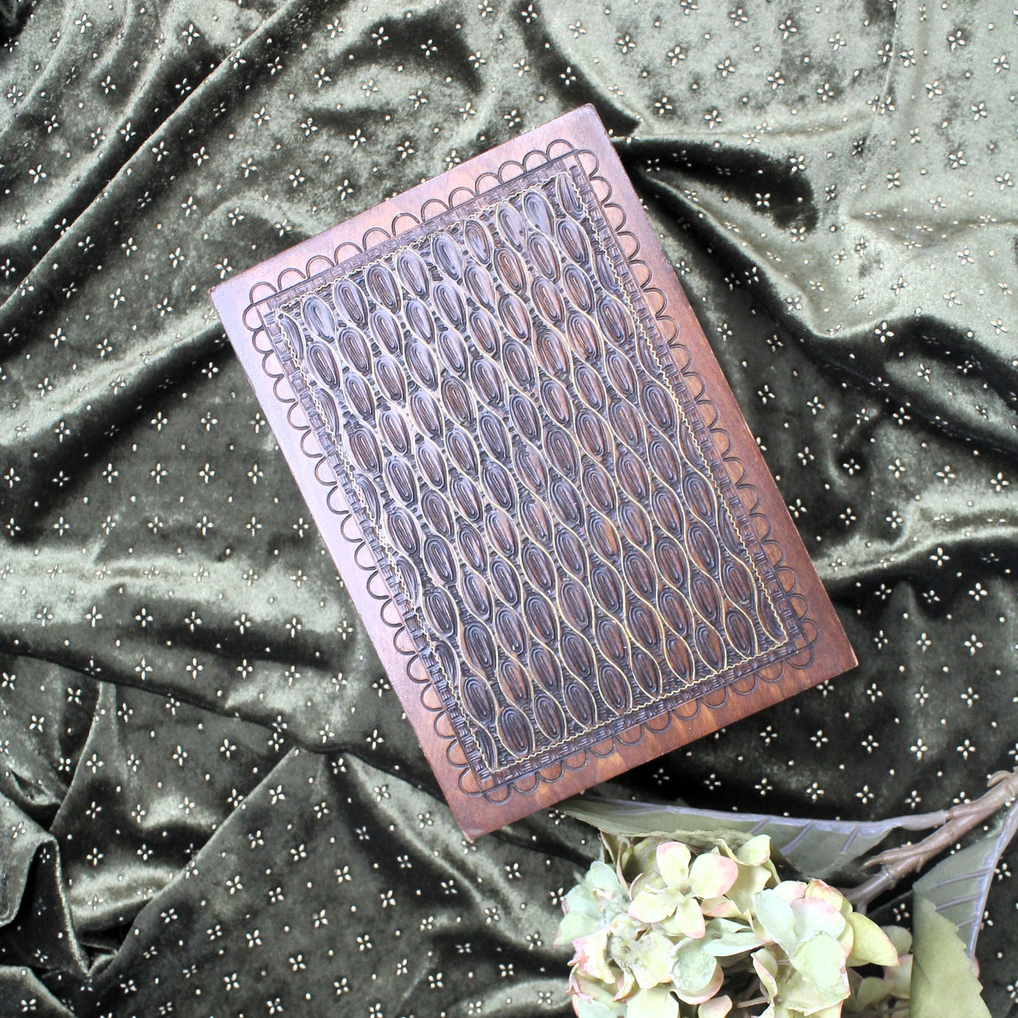Decorative wooden jewellery box on a textured fabric background with flowers