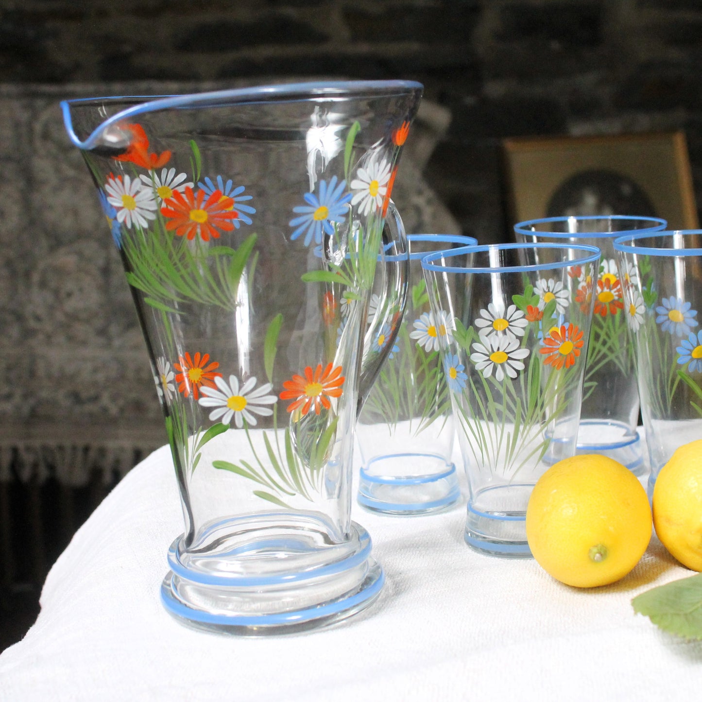 Clear glass pitcher and tumblers with floral designs on a white surface.