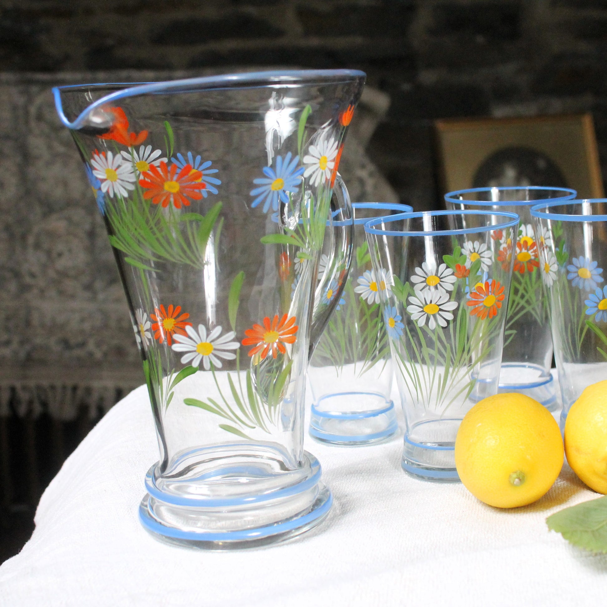 Clear glass pitcher and tumblers with floral designs on a white surface.