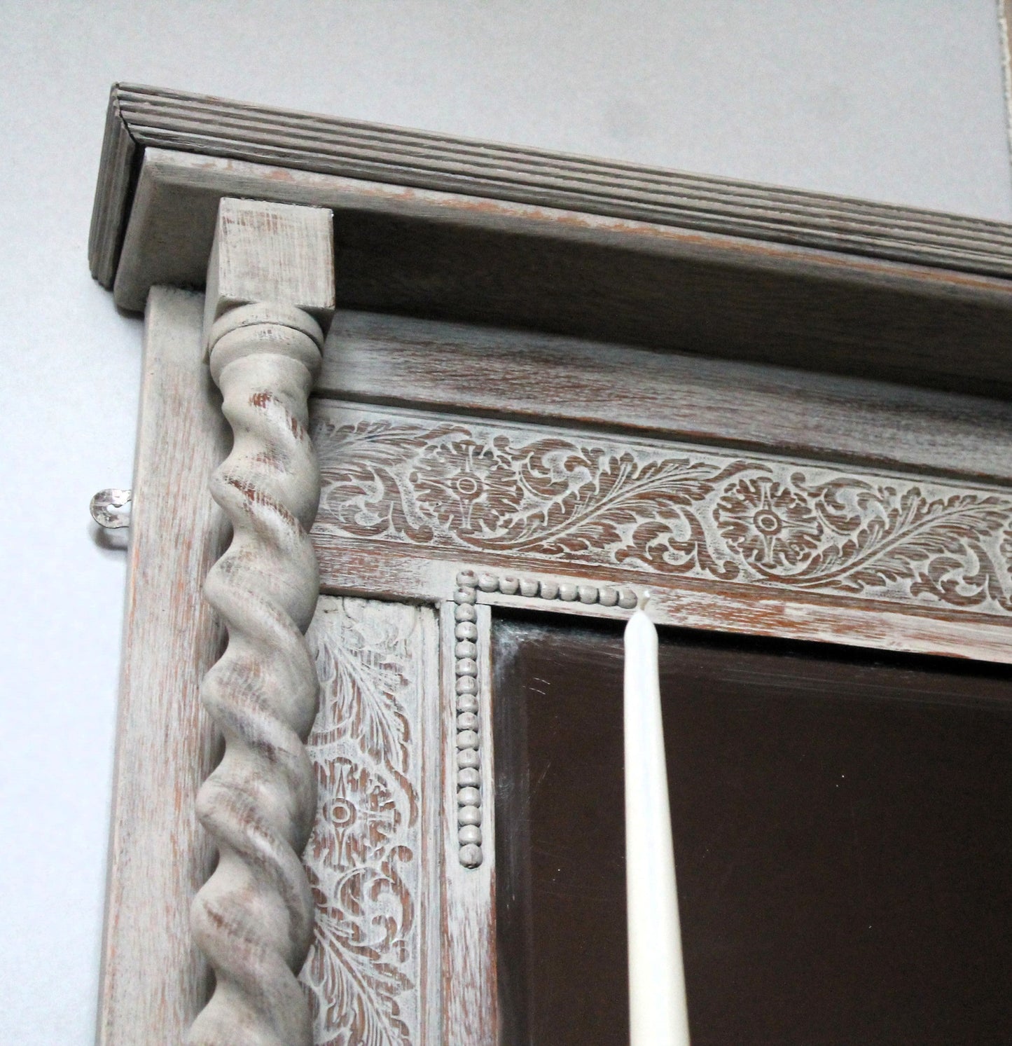 Decorative wooden mirror with intricate carvings on a white wall