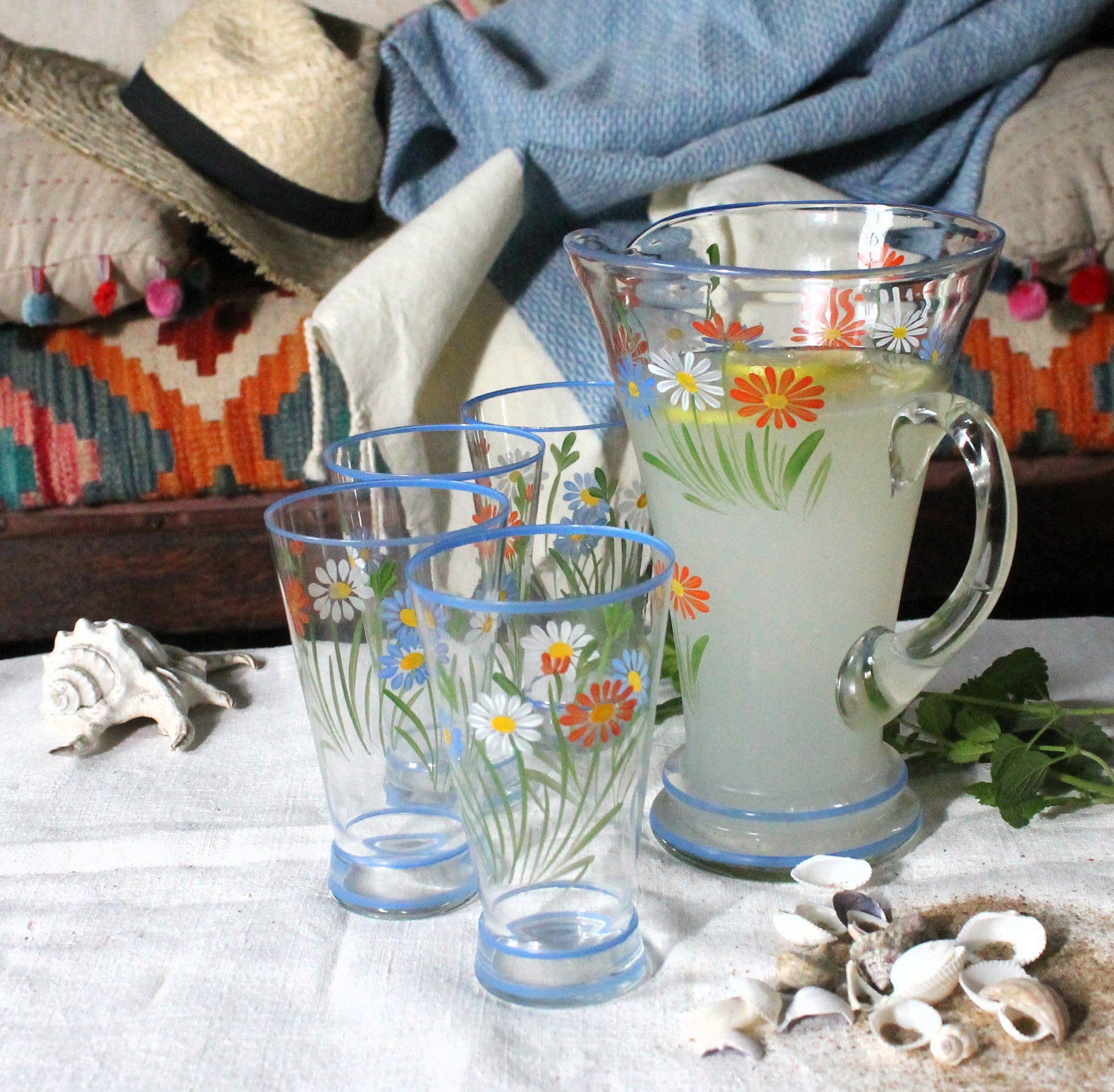 Decorative glassware with floral patterns on a tablecloth with a coastal theme.