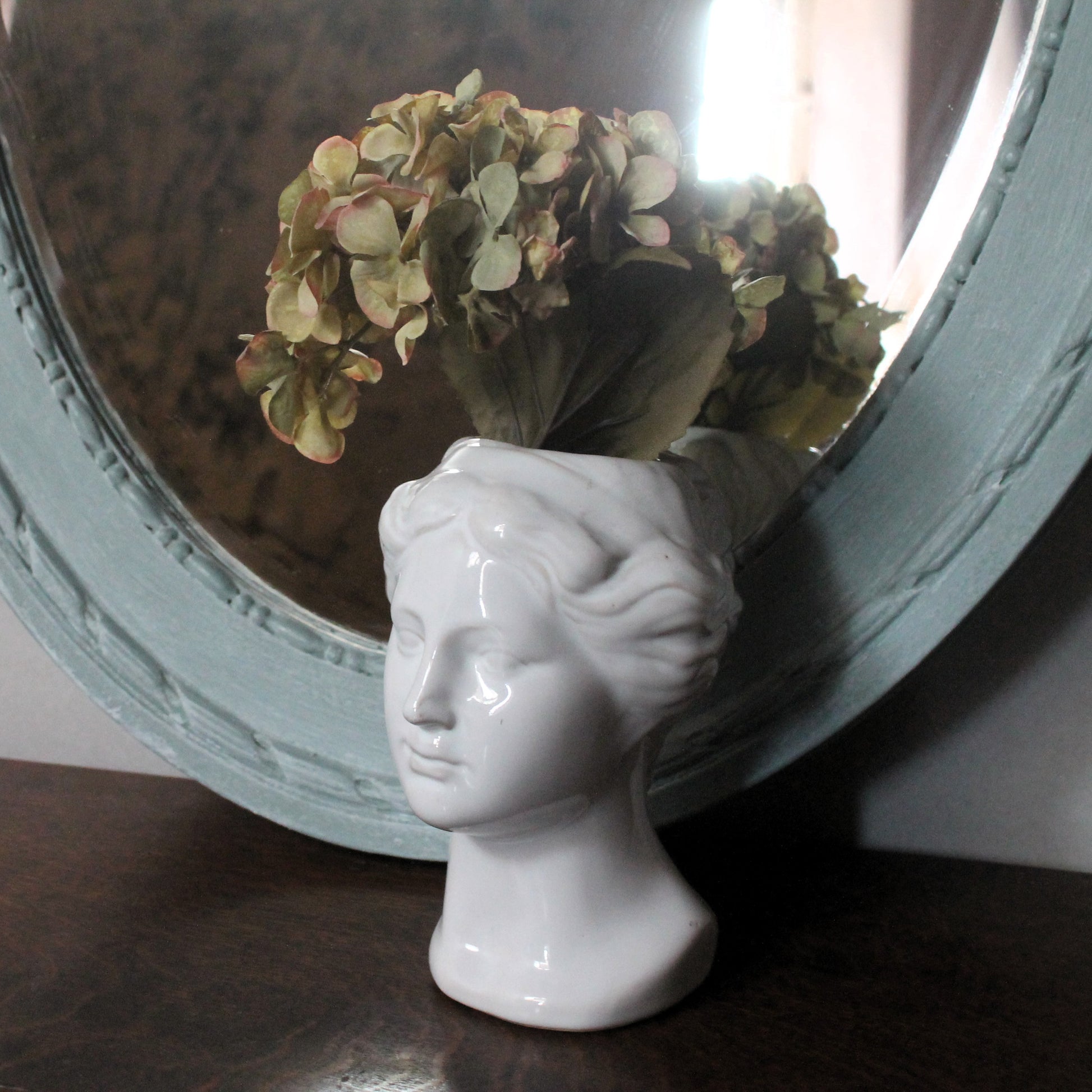 Blue neoclassical mirror with a white vase
