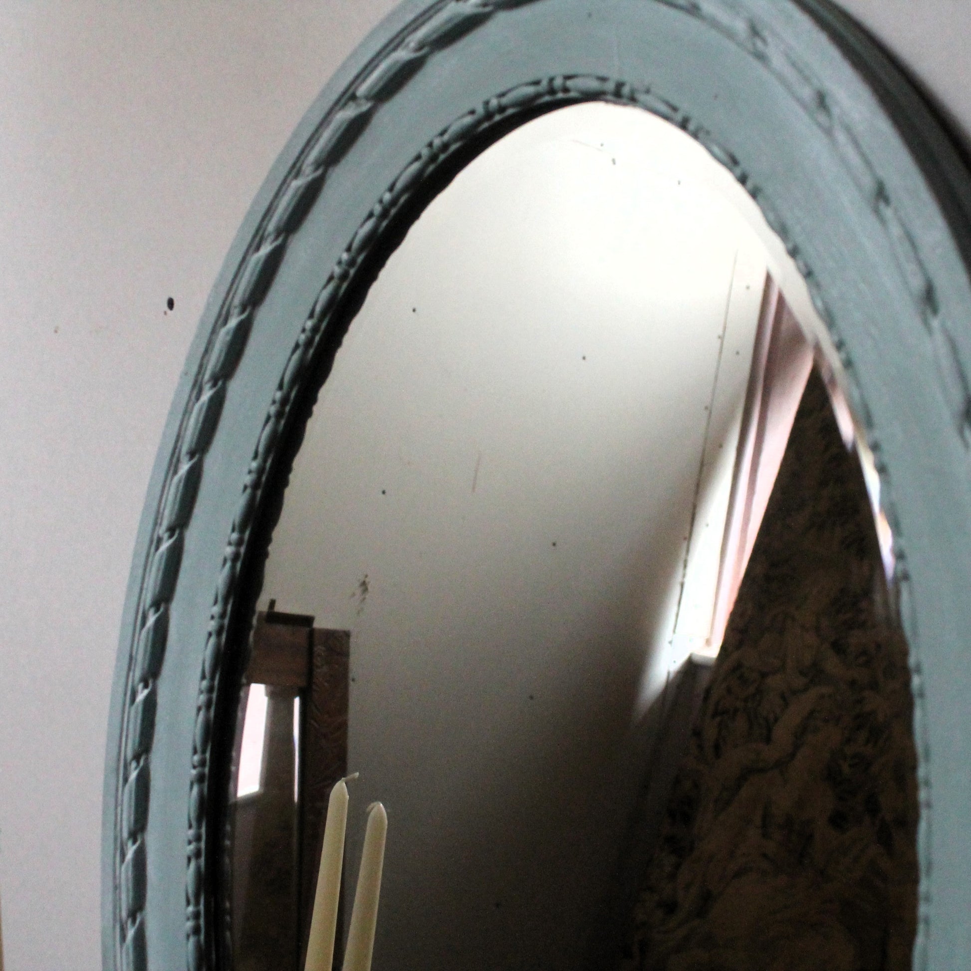 Decorative mirror with intricate frame on a plain wall