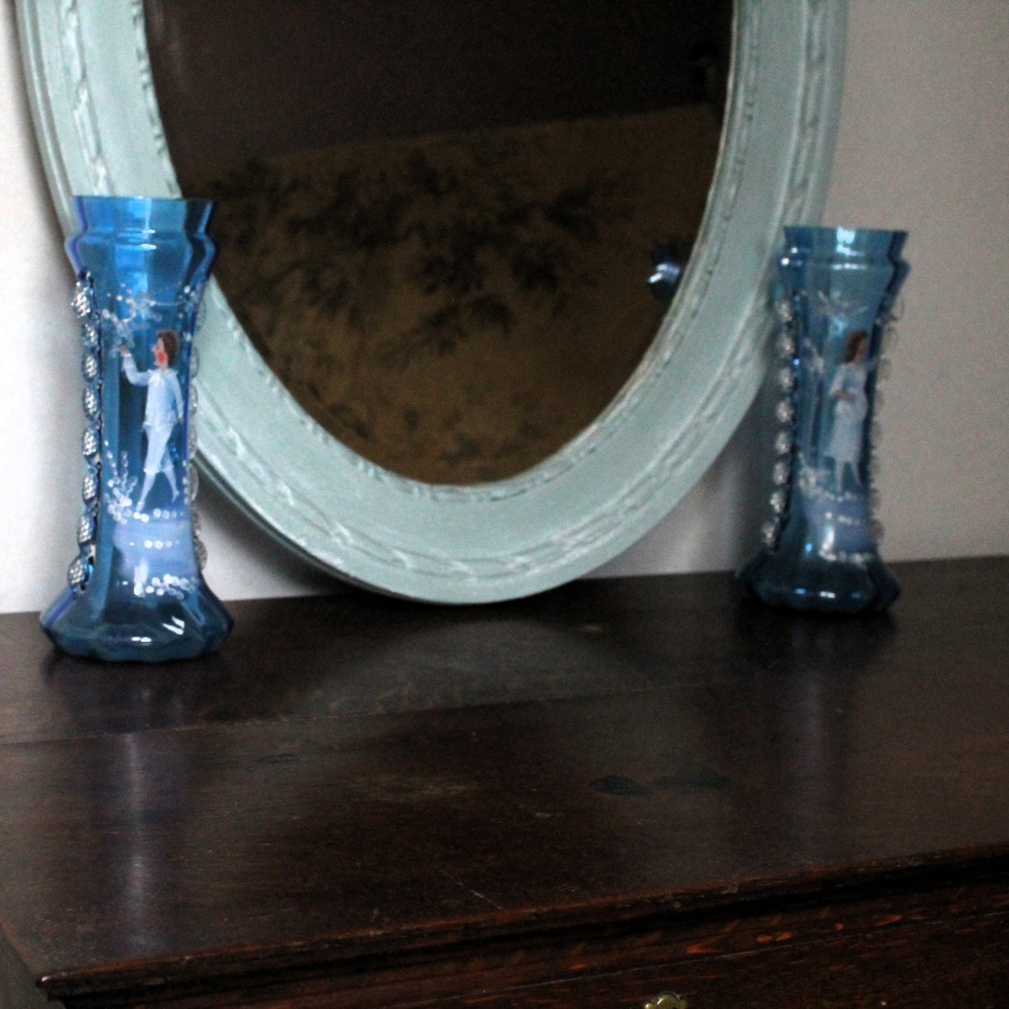 Pair of bue Mary Gregory vases in front of a mirror