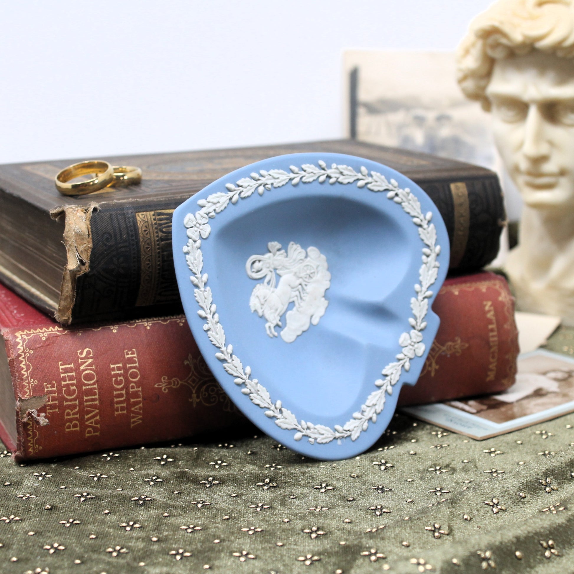 Blue decorative Wedgewood Jasperware dish with white emblem on top of books