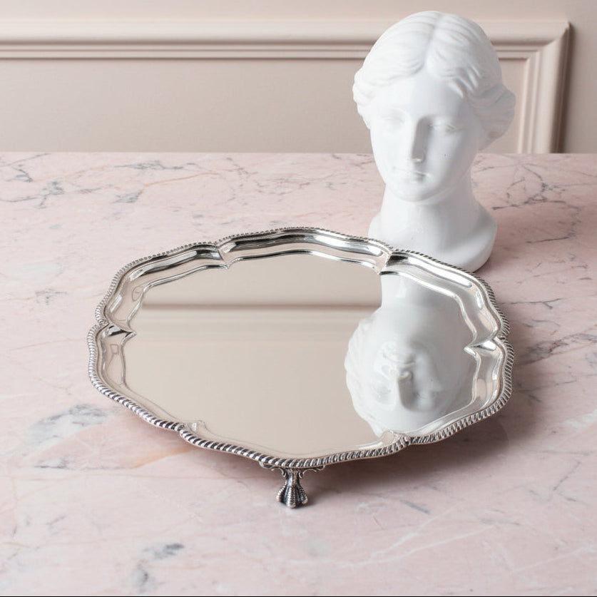 A round Walker & Hall Sterling silver tray with a scalloped edge and decorative beaded rim, displayed a marble tabletop 