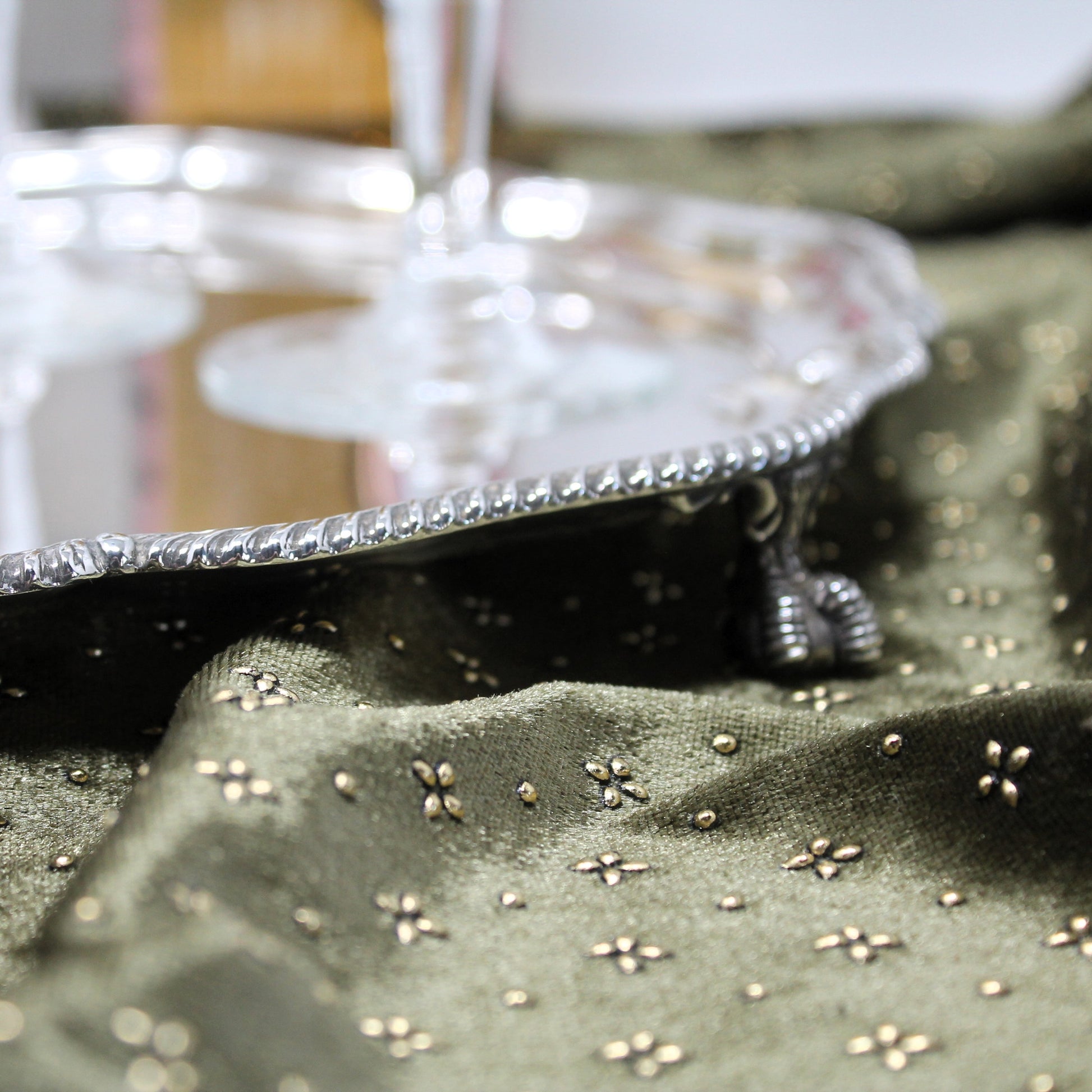 A close-up of the claw feet  beneath a walke & Hall Sheffield silver tray with a glass stem visible in the background.