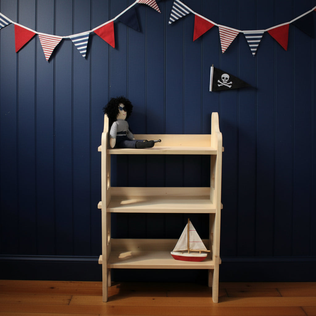 A light natural wood three-tier shelving unit with a small pirate doll sitting on the top shelf, set against a plain navy wall and dark wooden floor.