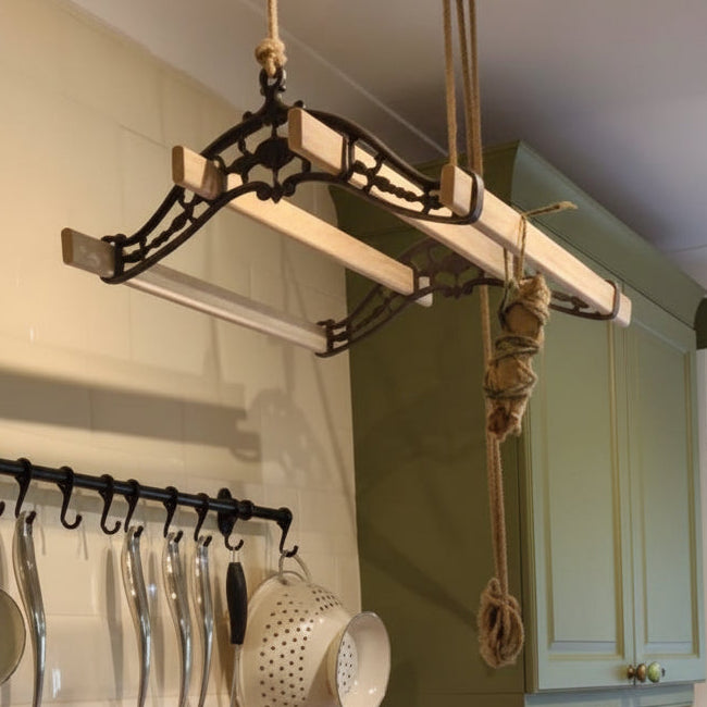 A cozy kitchen scene with cream cabinets, a white subway tile backsplash, a black gas stove, hanging utensils, and a green ceramic teapot in the foreground. No person or animal is present, but this is a real interior environment rather than a clean isolated product shot, so subject_type is Lifestyle.