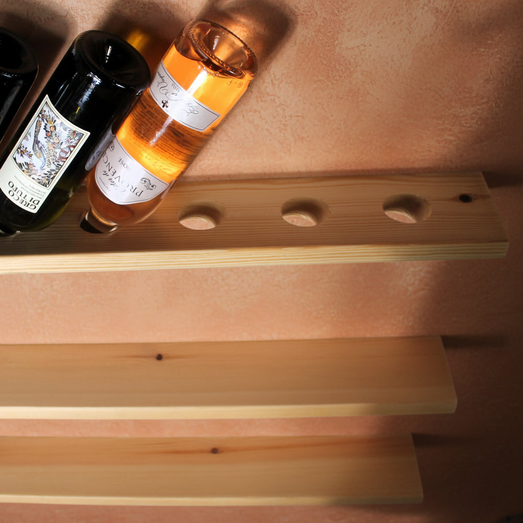 Three light natural wood floating shelves with oval cutouts, shown against a peach wall with wine bottles partially resting on the top shelf.