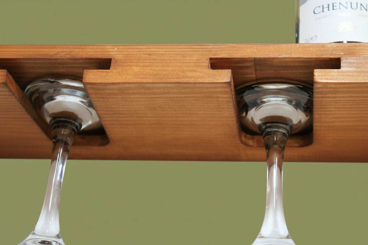 A close-up of a wooden wine glass holder with two wine glasses inserted into the slots, against a white background.